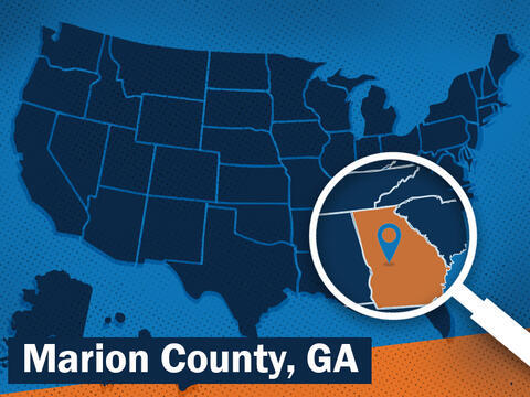 A magnifying glass focuses on the state of Georgia on a blue map of the USA. 