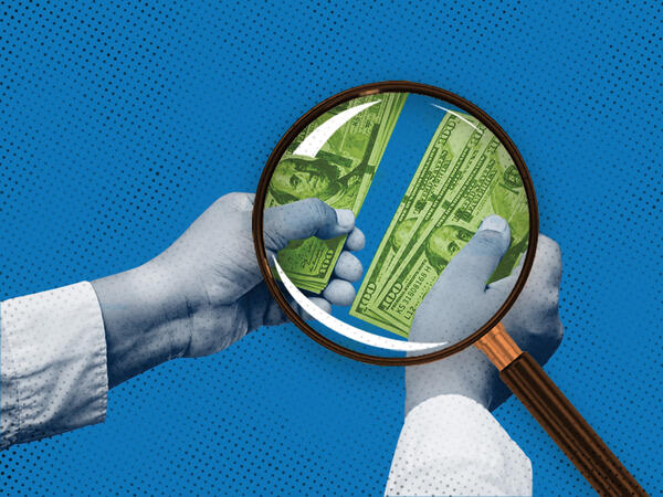 Magnifying glass looking at money on a blue background